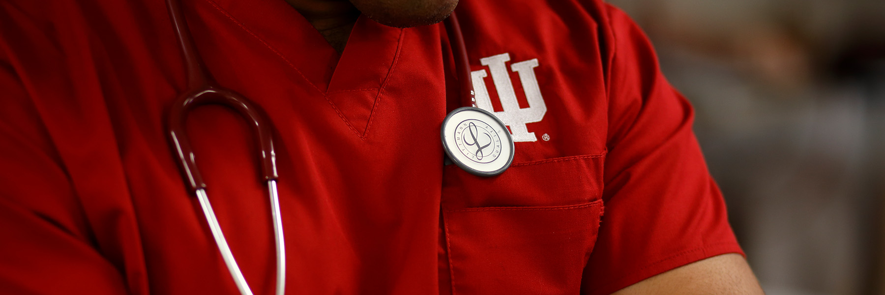 Photo of a nursing student in crimson scrubs with IU logo. 