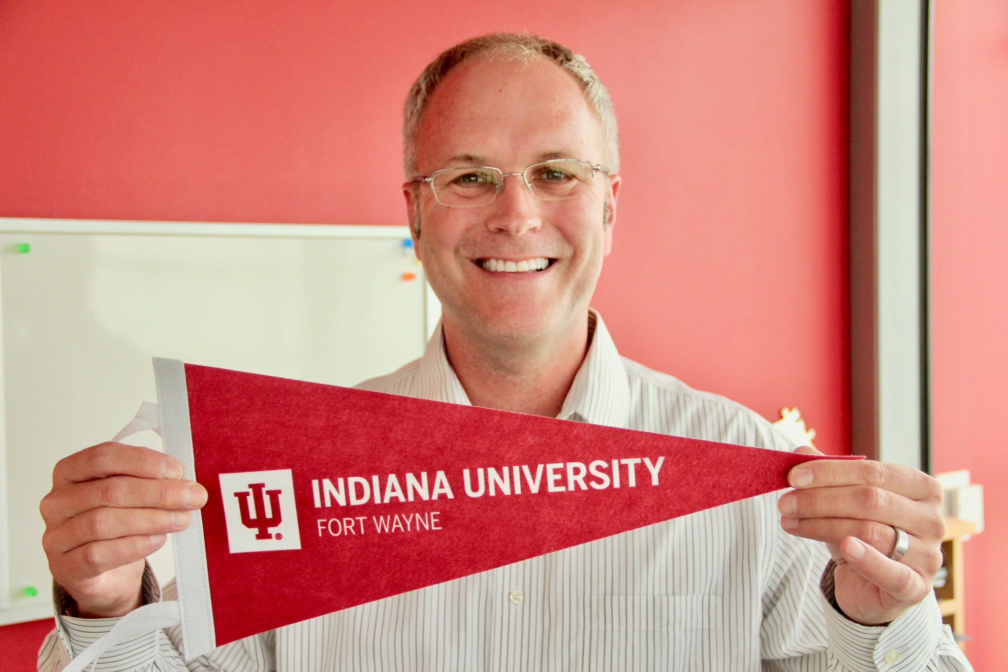 Dr. Boyd Bradshaw holding an IU Fort Wayne pennant.